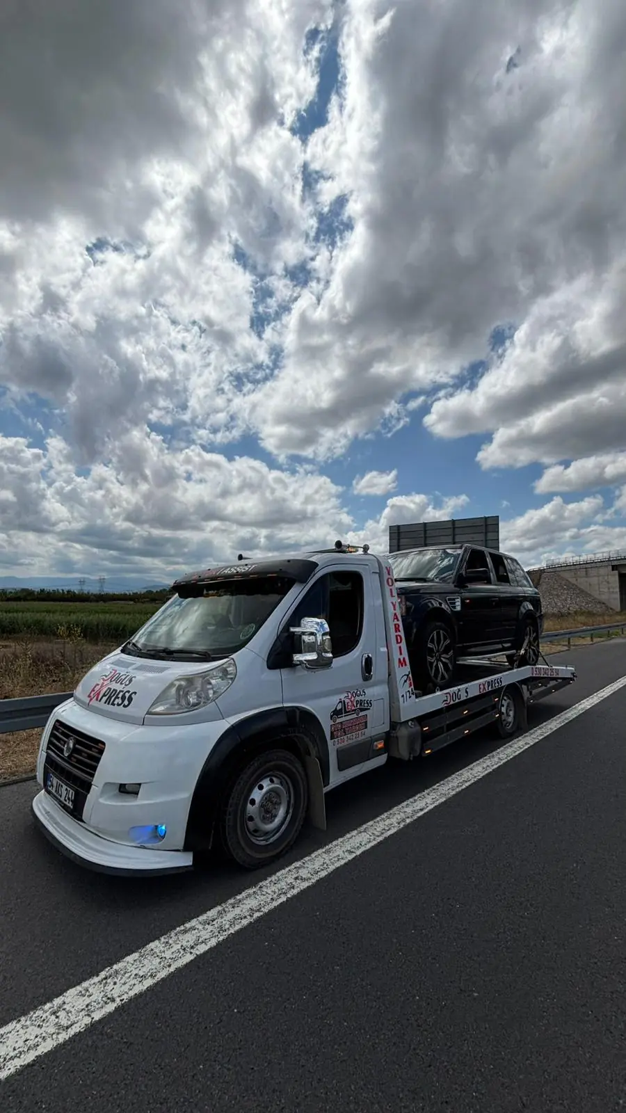 Doğuş Express platformlu çekici, otoyol kenarında siyah bir SUV'yi taşırken